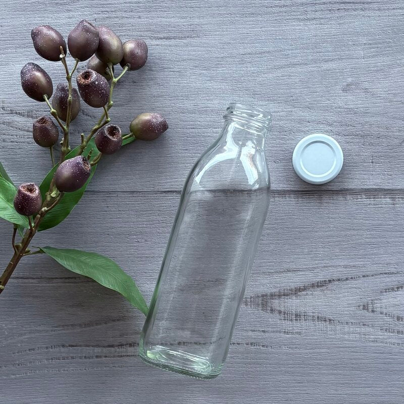 750ml clear glass juice bottle with white metal lid next to bottle