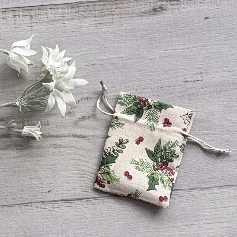 Beige Christmas fabric drawstring gift pouch decorated with red berries and green holly leaves, measuring 10 x 12.5cm.