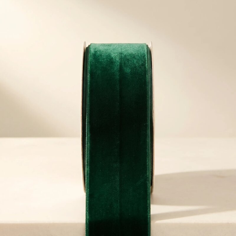 Roll of green velvet ribbon on a beige background