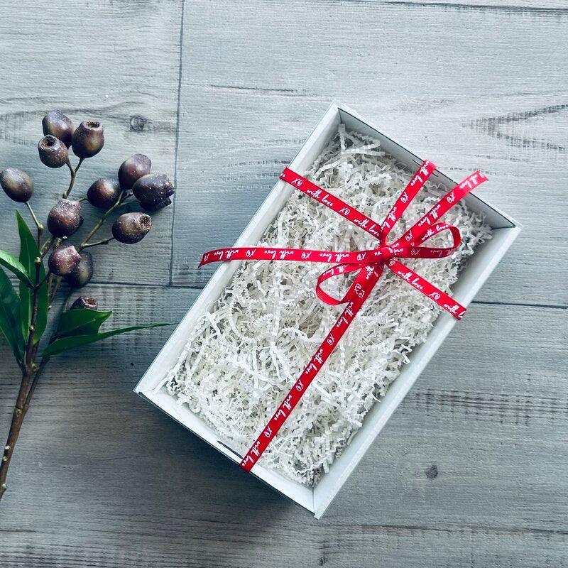 white small hamper with white shred and red ribbon