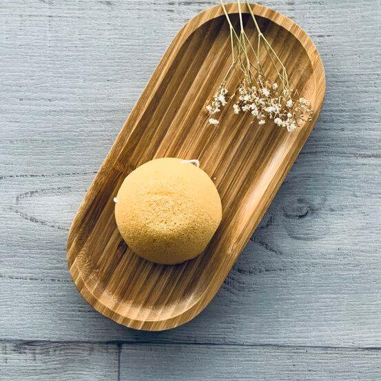 Konjac Facial Sponge - Tumeric - sitting on wood tray centaur packaging