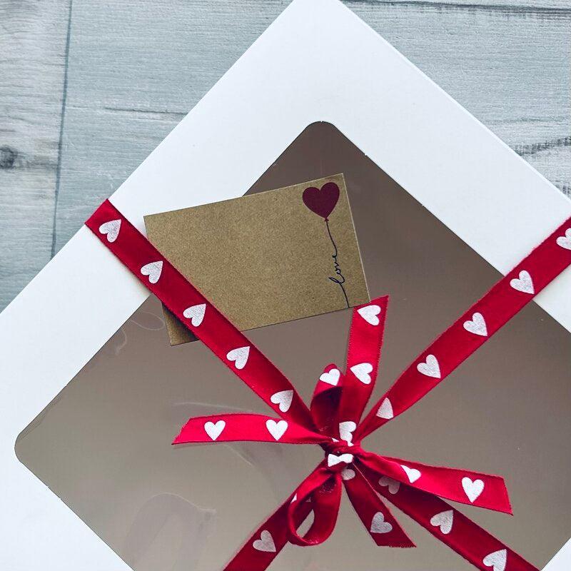 white cake box with red and white heart ribbon with love card