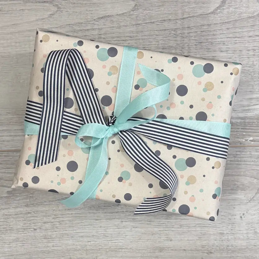 wrapped in confetti wrapping paper with grosgrain ribbon in peacock and navy stripe