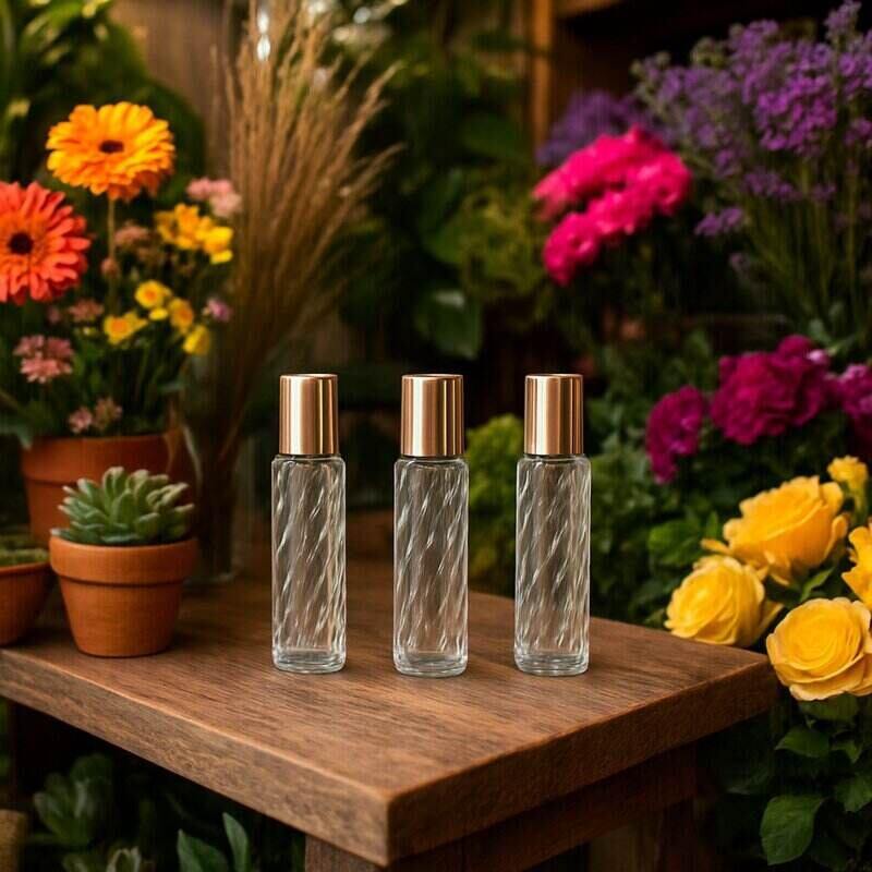 Three glass bottles with gold caps on a wooden surface surrounded by flowers
