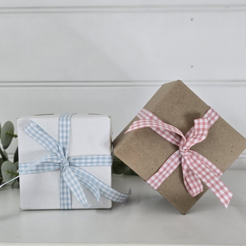 Two gift boxes with ribbons on a light gray surface