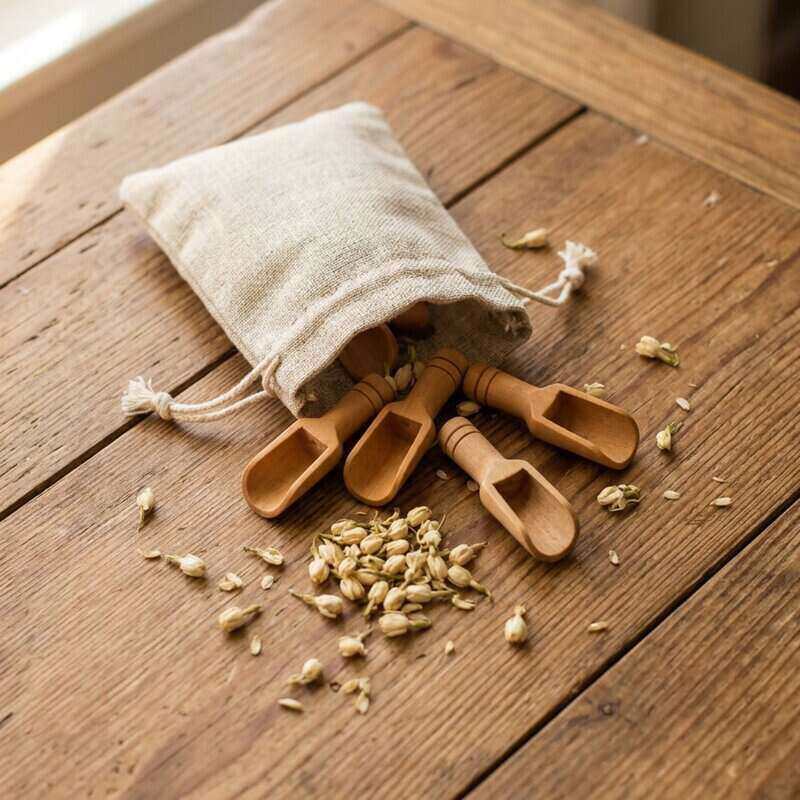 Set of wooden tea scoops with a fabric bag on a wooden surface