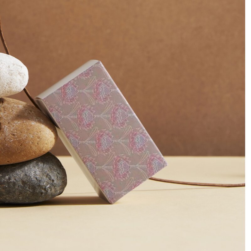 wrapped gift with a decorative cover leaning against stones on a beige surface