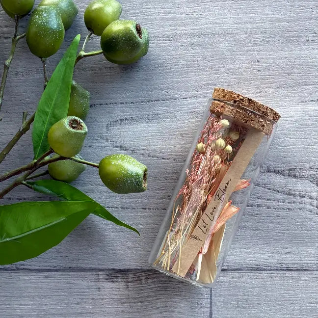 glass test tube with cork lid filled with botanicals pink 'let love bloom' printed card