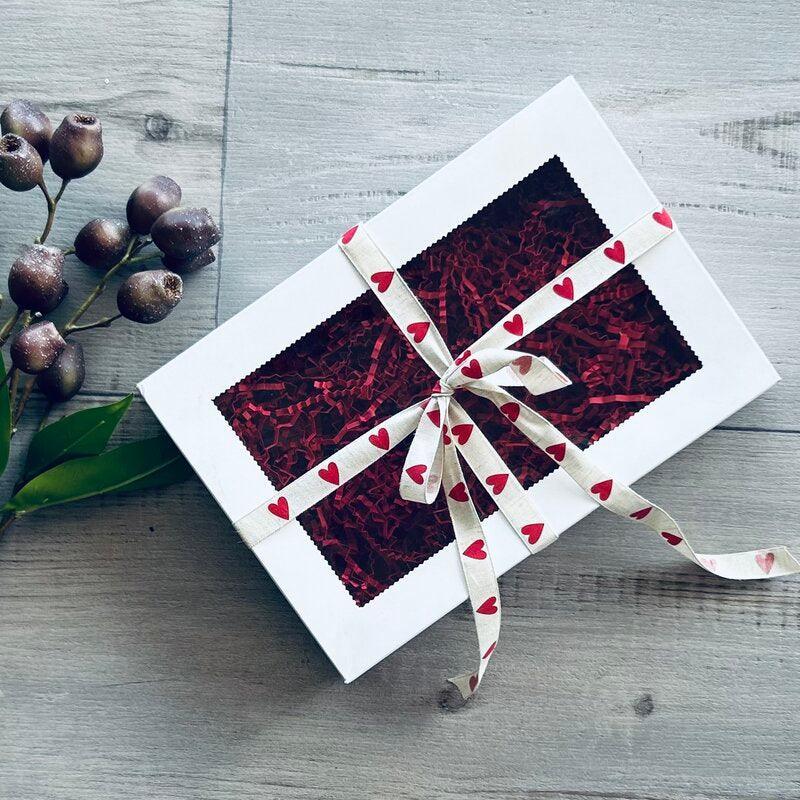 white cookie box with red shred and red heart ribbon